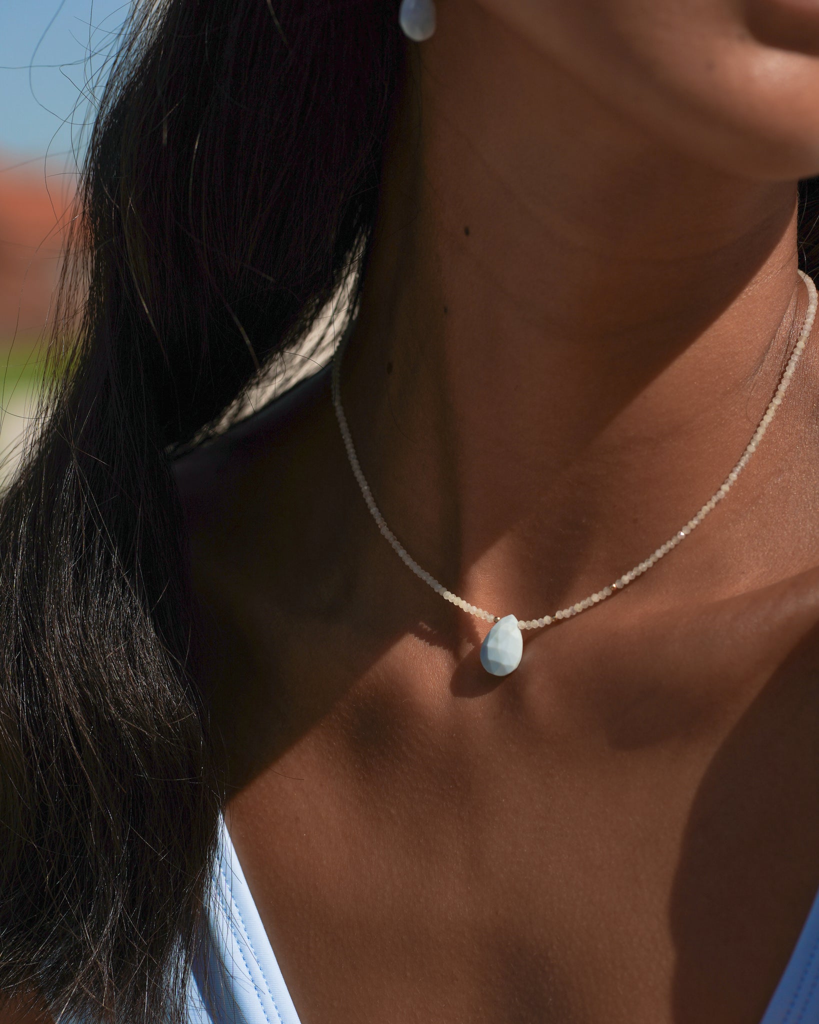 Model wearing blue opal pendant necklace with prehnite gemstone.
