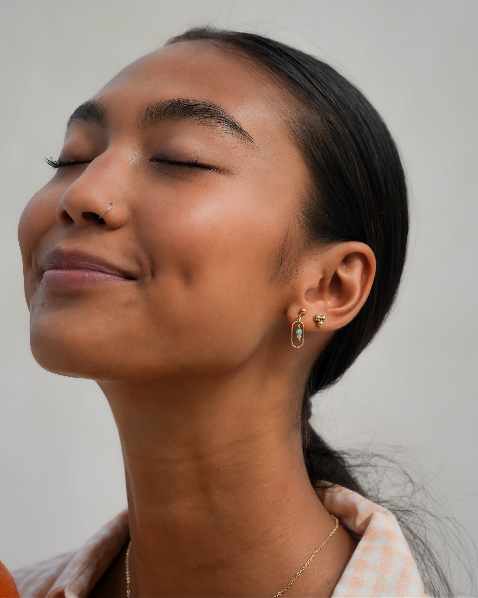Model wearing our minimalist earrings stack with Amazonite and moostone gemstones from Inari Jewellery's Tropical State of Mind collection