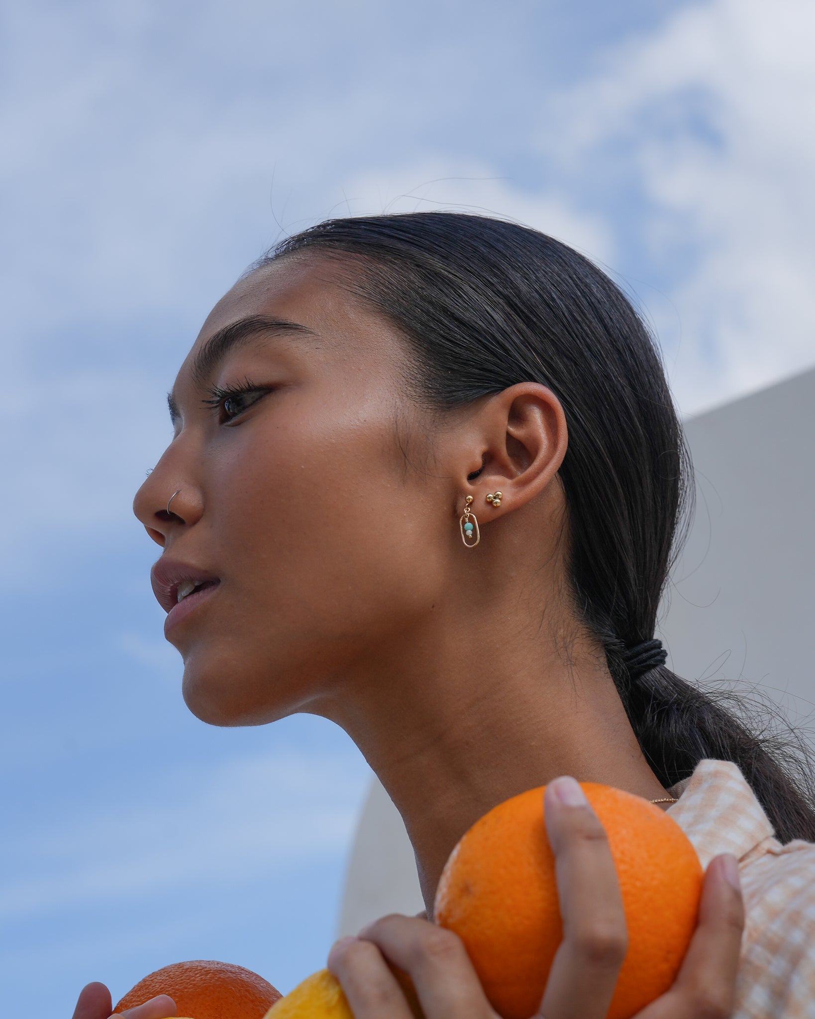 Model wearing Inari Jewellery's Nami earrings featuring moonstone and amazonite green gemstones
